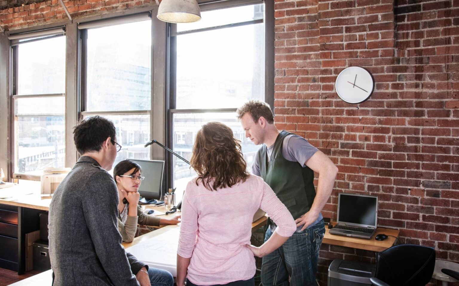 Team bespricht Markenkonzepte in einem Büro mit Backsteinwand